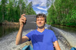 © Tatyana_Andreyeva - Handsome middle-aged man floating on boat along northern river and taking selfie with smartphone on beautiful landscape background in sunny summer day. Travel concept. Chernaya river, Karelia, Russia