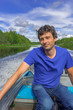 © Tatyana_Andreyeva - Handsome middle-aged man sitting at boat stern and floating along northern river on beautiful landscape background in summer day. Travel concept. Chernaya river, Karelia, Russia