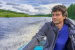 © Tatyana_Andreyeva - Handsome middle-aged man sitting at boat stern and floating along northern river on beautiful landscape background in summer day. Travel concept. Chernaya river, Karelia, Russia