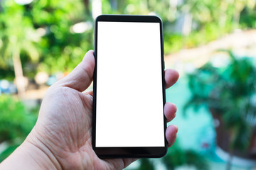 Mockup image of hand holding new black mobile phone with blank screen with green nature bokeh background