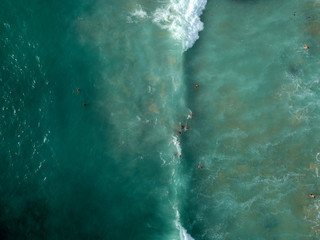  Aerial view of people swimming on waves in sea, ocean on Dreamland beach, Bali, Indonesia.