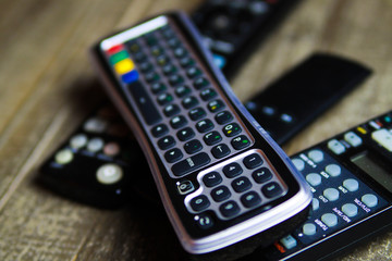 Close up of remote controls for TV, Video and stereo music system on wood table