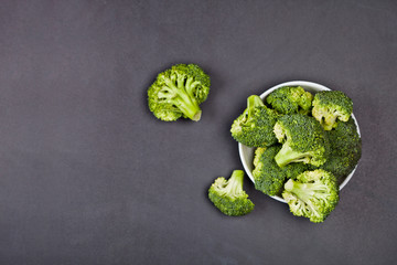 Canvas Print - Fresh green organic broccoli in white bowl on black board background.