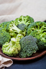 Canvas Print - Fresh green organic broccoli in brown plate and linen napkin.