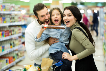 Family with shopping cart with food visiting supermarket