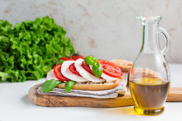 Canvas Print - Caprese sandwich: Mozzarella, tomatoes, basil leafes, italian bread, olive oil. Olive oil bottle. white background