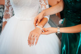 Fototapeta Boho - Bridesmaid helps to wear bracelet on the brides hand