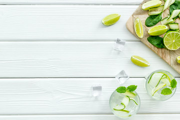 summer cocktails for freshness with lime, mint, cucumber and spinach and ice on white background top view mockup