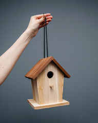 Adult woman hand holding hanged by a thread birds nesting birdhouse house ready to be installed in the garden on a tree