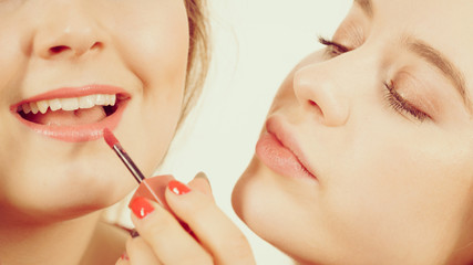 Poster - Woman applying her friend lipstick on lips