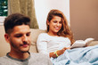© Manu Reyes - Young smiling heterosexual couple together on sofa