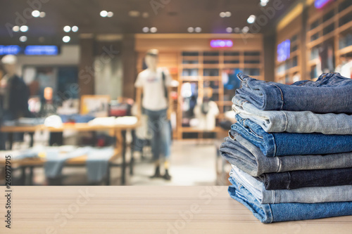 Fotomural Blue denim jeans stack on wood table top with abstract blur clothing store in mo