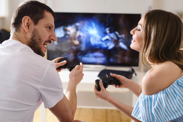 Beautiful couple playing fighting video games on console and having fun together