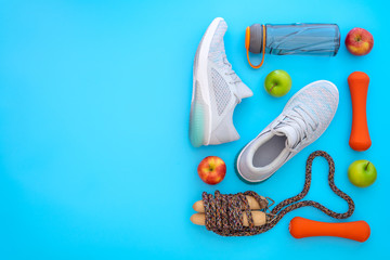 Wall Mural - Fitness, healthy and active lifestyles love concept, dumbbells, sport shoes, bottle of waters, apples, and jump rope in heart shape on light blue background. Top view with copy space.