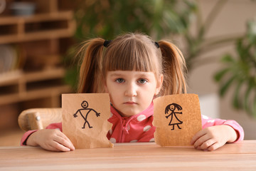 Poster - Sad little girl with torn drawing of family at table. Concept of divorce