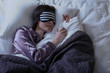 © Pixel-Shot - Young woman with sleep mask in bed at night