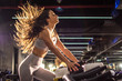 © Bojan - Attractive young sportswoman with long hair in the air riding stationary bike during cycling training in gym