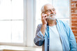 © rh2010 - Cheerful senior grandfather talking with phone near the window at home