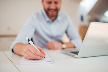 Wall Mural - Entrepreneur writing notes sitting at his desk.