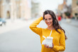 © bnenin - Girl with takeaway box standing in the city street, smiling at camera, copy space.