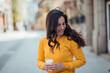 © bnenin - Cheerfull millenial woman walking in the city with takeaway coffee.