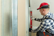 © artursfoto - Man holding level against plasterboard, interior drywall. Attic renovation