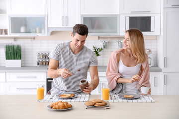 Poster - Happy couple having breakfast together in kitchen