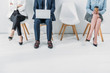 © LIGHTFIELD STUDIOS - cropped view of women sitting with crossed legs and crossed arms near man using laptop