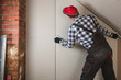 © artursfoto - Man installing plasterboard sheet to wall for attic room construction