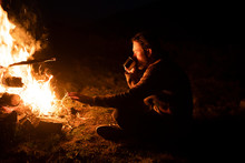 Man Drinking By Campfire
