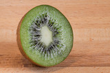 Fototapeta  - Half of a cut kiwi fruit on a wooden board