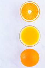 Wall Mural - Orange fruits with juice, concept. Orange juice and halves of oranges on white background. Citrus for making juice. Whole and squeezed oranges and glass of juice