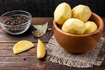 Wall Mural - Peeled potato on dark wooden background. 