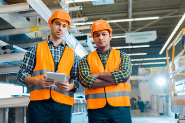 Wall Mural - serious multicultural workers in safety vasts and helmets looking at camera