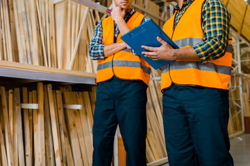 Wall Mural - partial view of workers standing near shelves with wooden construction materials