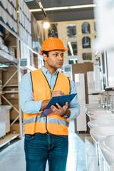 Wall Mural - selective focus of attentive indian man writing in clipboard in plumbing department