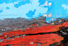 Close Up Detail Of An Old Boat's Hull Forms An Abstract Textured Background Of Old Decaying Wooden Boat Panels With Colorful Bands Of Bright Red And Sky Blue Peeling Paint.
