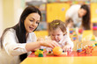 © Oksana Kuzmina - Nursery baby and teacher play with developmental toys in preschool