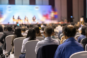 rear view of audience listening speakers on the stage in the conference hall or seminar meeting, bus