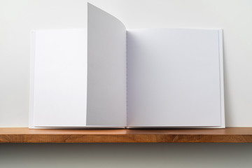 white square notebook on bookshelf and white wall