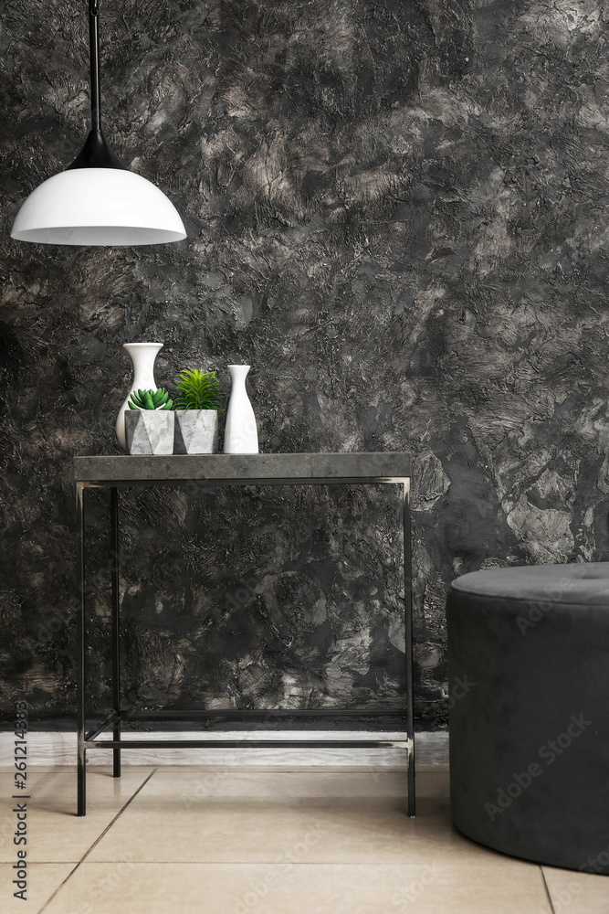 Table and pouf near dark wall