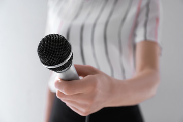 Female journalist with microphone on light background, closeup