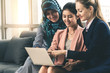 © InfiniteFlow - Multicultural working group. Team of businesswomen of different ethnicity, Caucasian, Asian and Arabic working together with laptop computer at office workplace. Multiethnic teamwork concept.