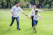 © iammotos - happy asian Family, parents and their children running around  in park together. father mother and son having fun and laughing outdoors . cheerful