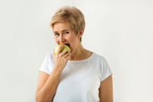 Beautiful Woman With A Short Haircut In A White T-shirt Bites An Apple