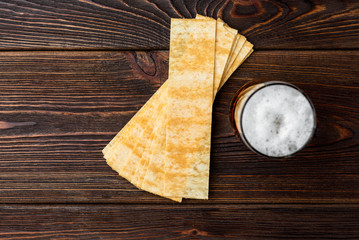 Wall Mural - Beer and crisps on dark wooden background.