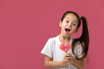 Wall Mural - Beautiful cute little child girl with sweet candy lollipop isolated on pink background