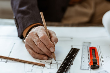 Close up of interior designer wearing dark jacket painting drafts