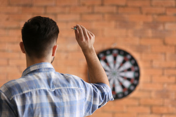 young man playing darts indoors
