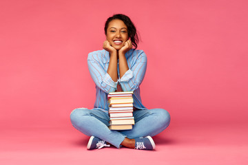 Sticker - education, high school and people concept - happy african american young student woman with books sitting on floor over pink background